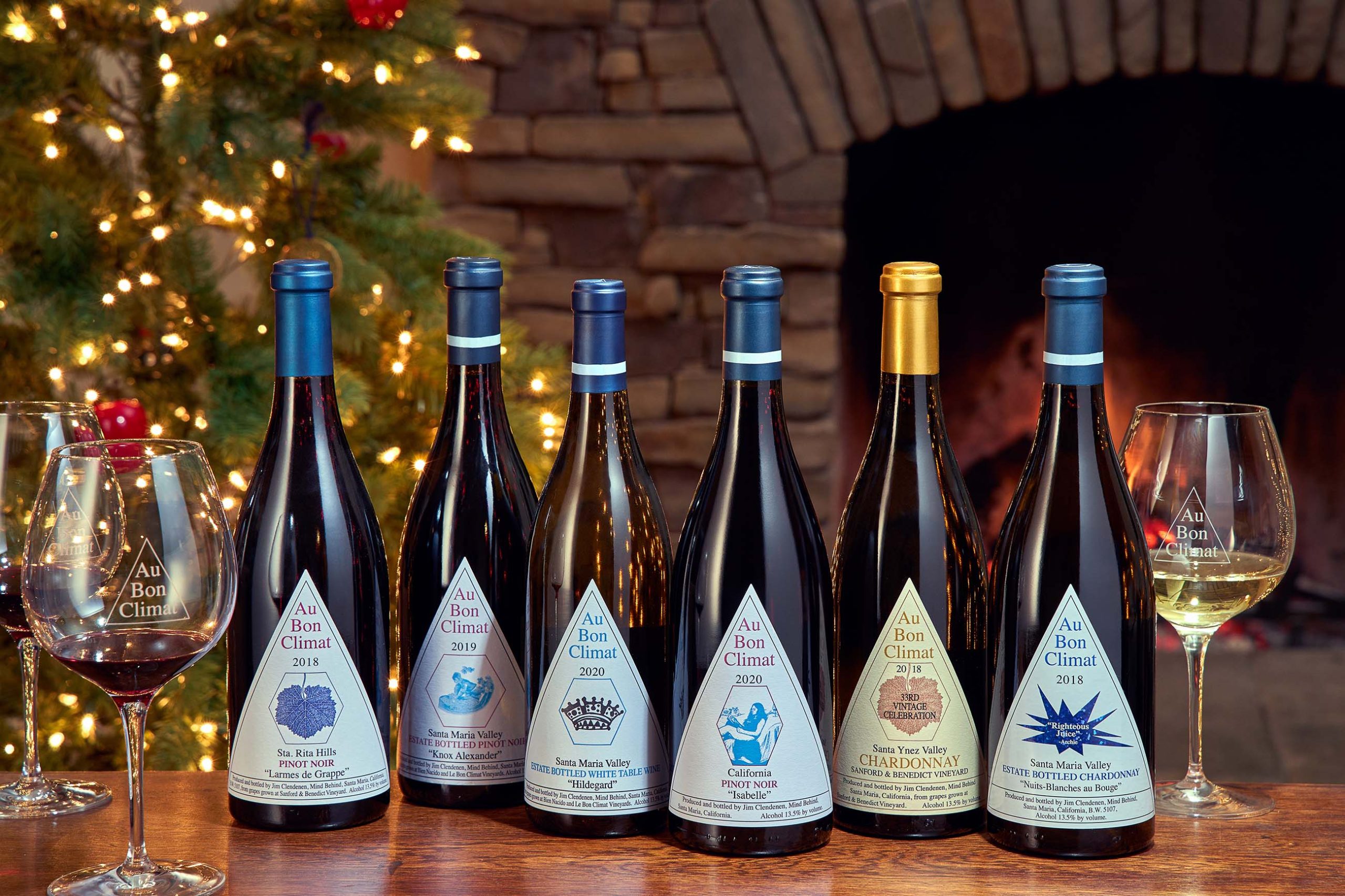 Six Au Bon Climat Wine Bottles in a row in front of a fireplace and a Christmas tree