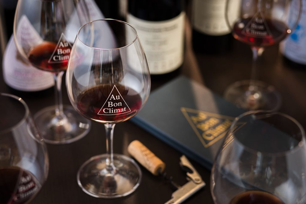 A view of Au Bon Climat red wine in a glass with a cork on the table next to the glass