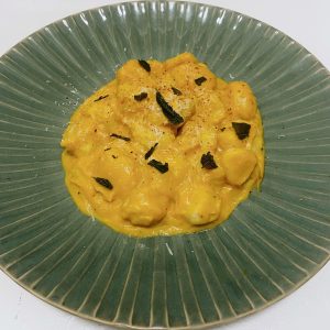 A green bowl of Handmade Rolled Gnocchi with Kabocha Cream Sauce.