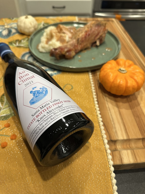 Bottle of Au Bon Climat 2021 Knox Alexander Estate Pinot Noir alongside a holiday plate of roasted meat and mashed potatoes with gravy.