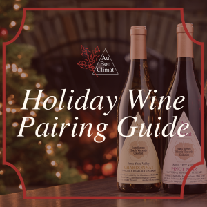 Au Bon Climat Holiday Wine Pairing Guide featuring Sanford & Benedict Vineyard Chardonnay and Pinot Noir beside festive wine glasses, a glowing Christmas tree, and a warm fireplace.